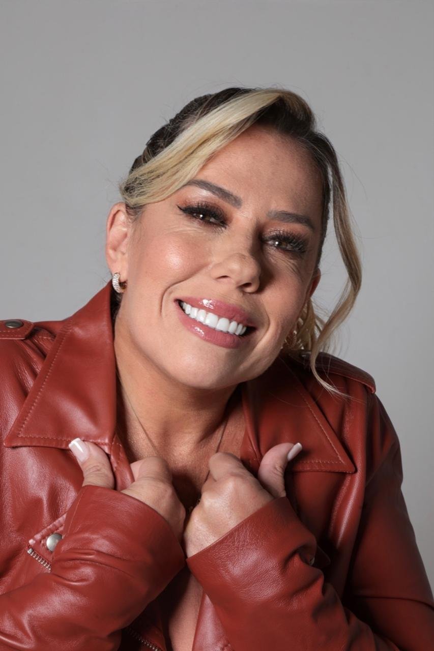 Retrato de Daniela Amorim sorrindo, de jaqueta vermelha, com as mãos no peito